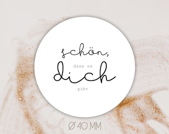 以下が含まれることがあります： 「schön, dass es dich gibt」と「Ø 40 MM」と書かれた黒いテキストと白い丸いステッカー。