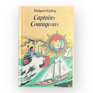 May include: A vintage paperback book with a yellow cover featuring an illustration of a ship and a boy in a red hat. The title of the book is "Captains Courageous" by Rudyard Kipling.