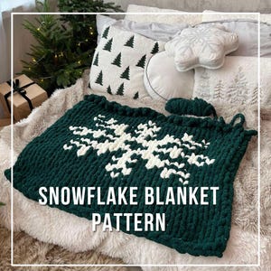 May include: A green and white knitted blanket with a snowflake pattern. The blanket is made with chunky yarn and has a soft, fluffy texture. The text "SNOWFLAKE BLANKET PATTERN" is printed on the blanket.