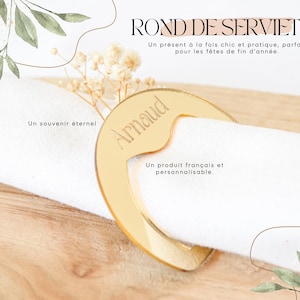Peut inclure: Un rond de serviette doré avec le nom "Arnaud" gravé, tenant une serviette blanche. Le texte "ROND DE SERVIETTE" et "Un produit français et personnalisable" sont également présents.
