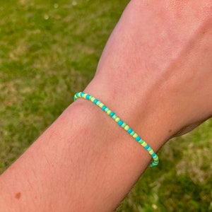 May include: A beaded bracelet with alternating turquoise and light green beads.