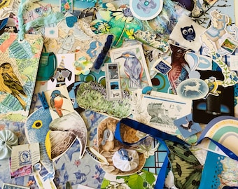 May include: A collection of blue and white paper ephemera, including birds, butterflies, flowers, and a small house. The ephemera is arranged on a blue and white patterned background.