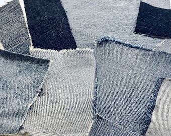 Puede incluir: Una colección de recortes de tela vaquera en varios tonos de azul, con bordes sin rematar. La tela está dispuesta en un patrón superpuesto, creando un efecto texturizado y en capas.
