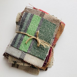 May include: A stack of fabric swatches tied together with twine. The swatches are in various colours and patterns, including green, brown, and red.
