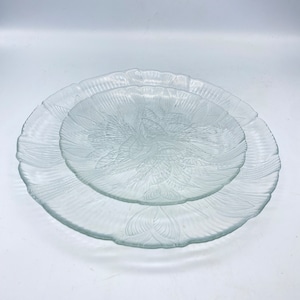 May include: Two clear glass plates with a decorative etched design. The plates are stacked on top of each other.