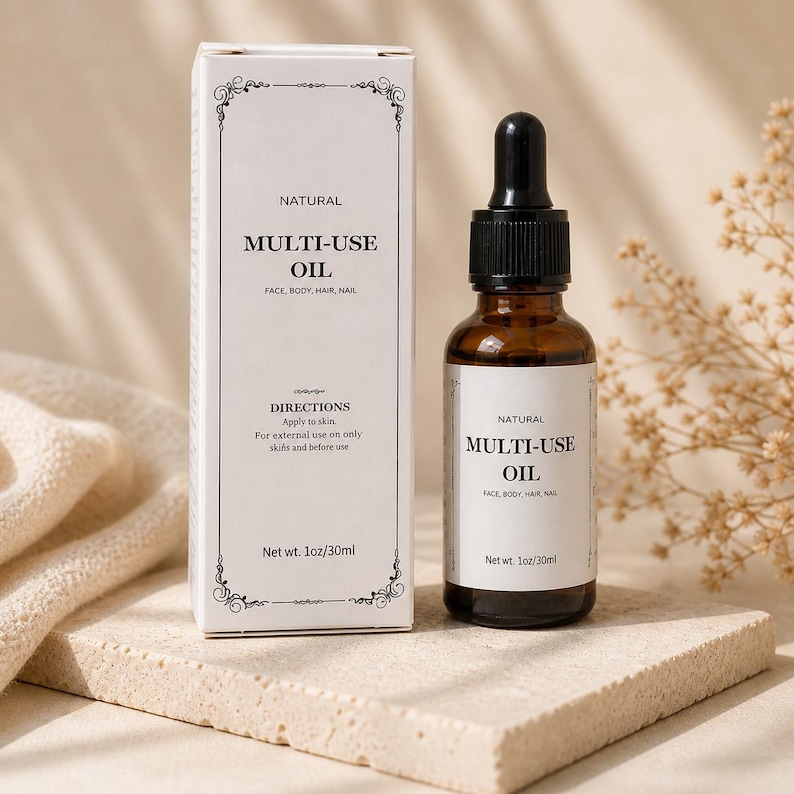 May include: A brown glass bottle with a black dropper and a white label that reads "NATURAL MULTI-USE OIL FACE, BODY, HAIR, NAIL". Beside it is a white box with the same text and "Net wt. 1oz/30ml".