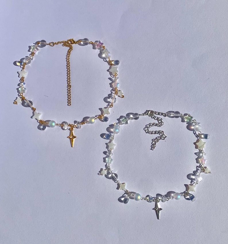 May include: Two delicate necklaces with iridescent star charms and crystal beads. Each necklace features a gold or silver star pendant.