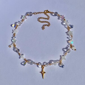 May include: A gold chain necklace with clear beads and star-shaped charms. The necklace has a gold star pendant.
