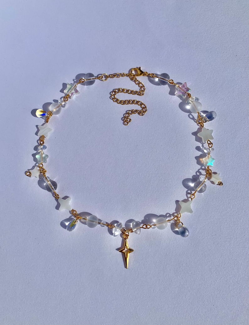May include: A gold chain necklace with clear beads and star-shaped charms. The necklace has a gold star pendant.