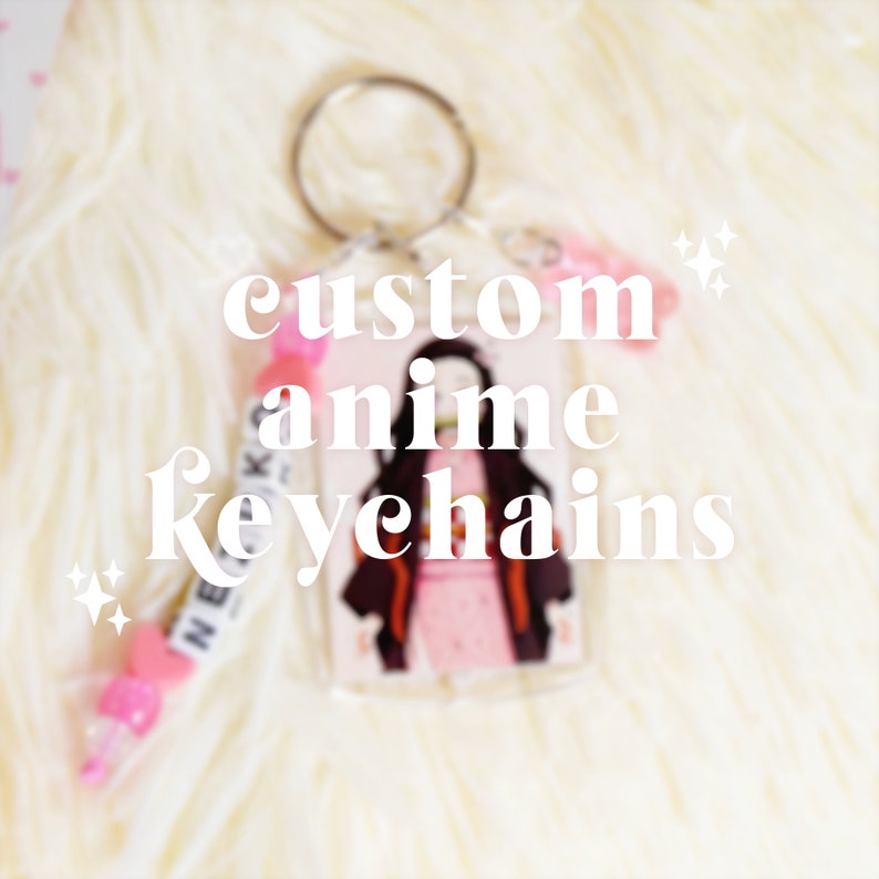 May include: Custom anime keychain featuring a character illustration. The keychain has a clear acrylic base with a silver keyring. The text "custom anime keychains" is displayed in white. A pink beaded charm is attached.