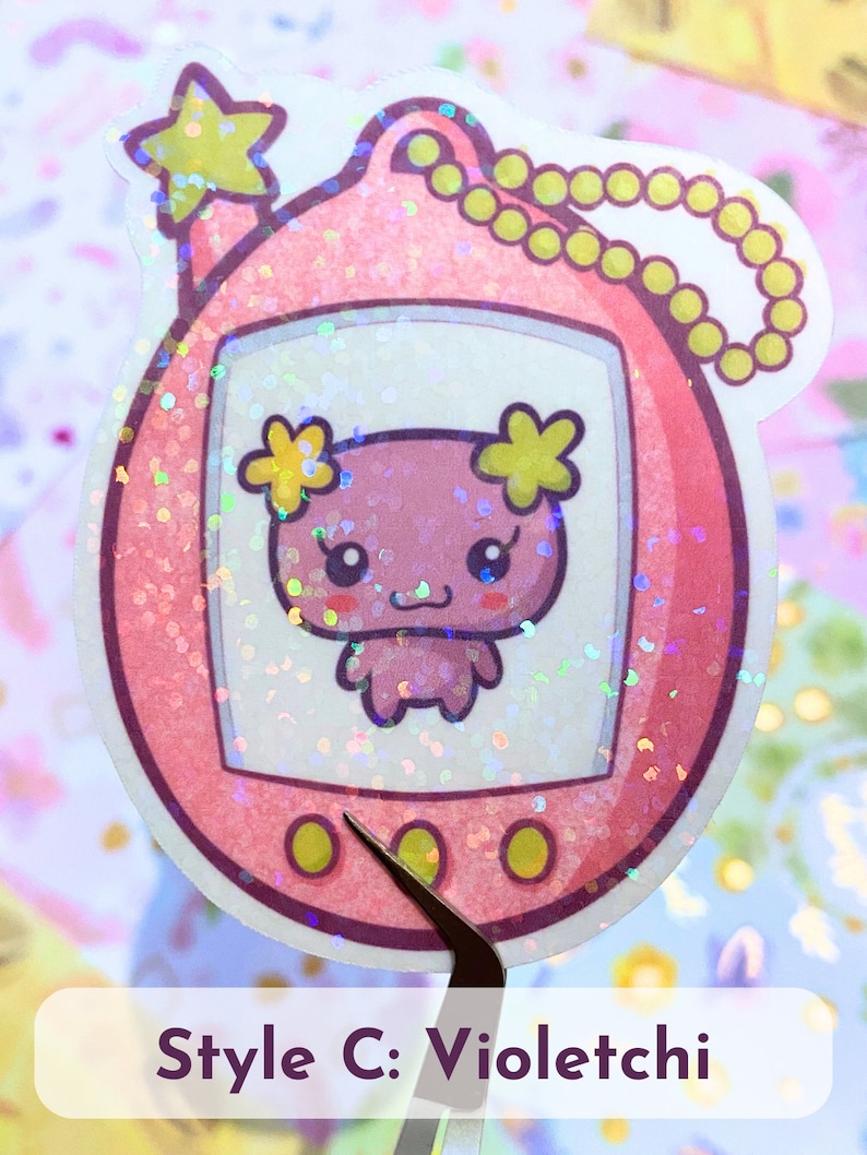 Może przedstawiać: Holograficzna naklejka w kolorze r&oacute;żowym i ż&oacute;łtym przedstawiająca cyfrowego zwierzaka w stylu Tamagotchi z r&oacute;żowym zwierzątkiem w środku. Naklejka ma gwiazdę na g&oacute;rze i ż&oacute;łtą pętlę łańcucha.