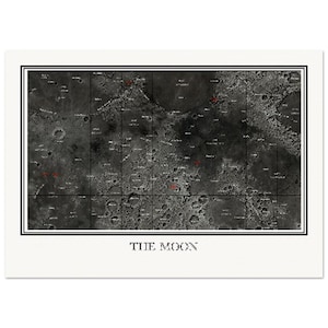 May include: A rectangular print featuring a detailed black and white lunar surface map with a grid overlay and small red markings. The text THE MOON is printed in a serif font centred below the image within a white border and black frame.