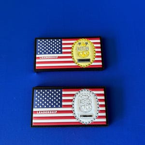 May include: Two black and white patches with an American flag on the left side and a gold and white US Navy emblem on the right side. The top patch says "LEADERSHIP" and "COMMAND" on the bottom patch.