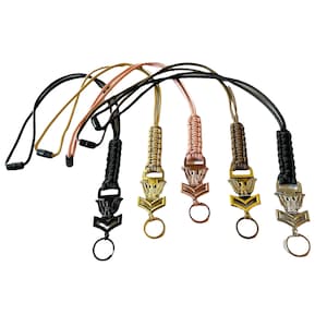 May include: Five different color paracord lanyards with a gold eagle and chevron charm. The lanyards are made with a braided paracord and have a metal ring at the bottom.