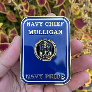 K&ouml;nnte beinhalten: Eine goldfarbene Metall-Challenge-M&uuml;nze mit blauem Hintergrund. Die M&uuml;nze zeigt den Text "NAVY CHIEF MULLIGAN" und "NAVY PRIDE" in goldenen Buchstaben. Ein goldfarbener Anker mit dem Text "USN" ist in der Mitte der M&uuml;nze platziert.