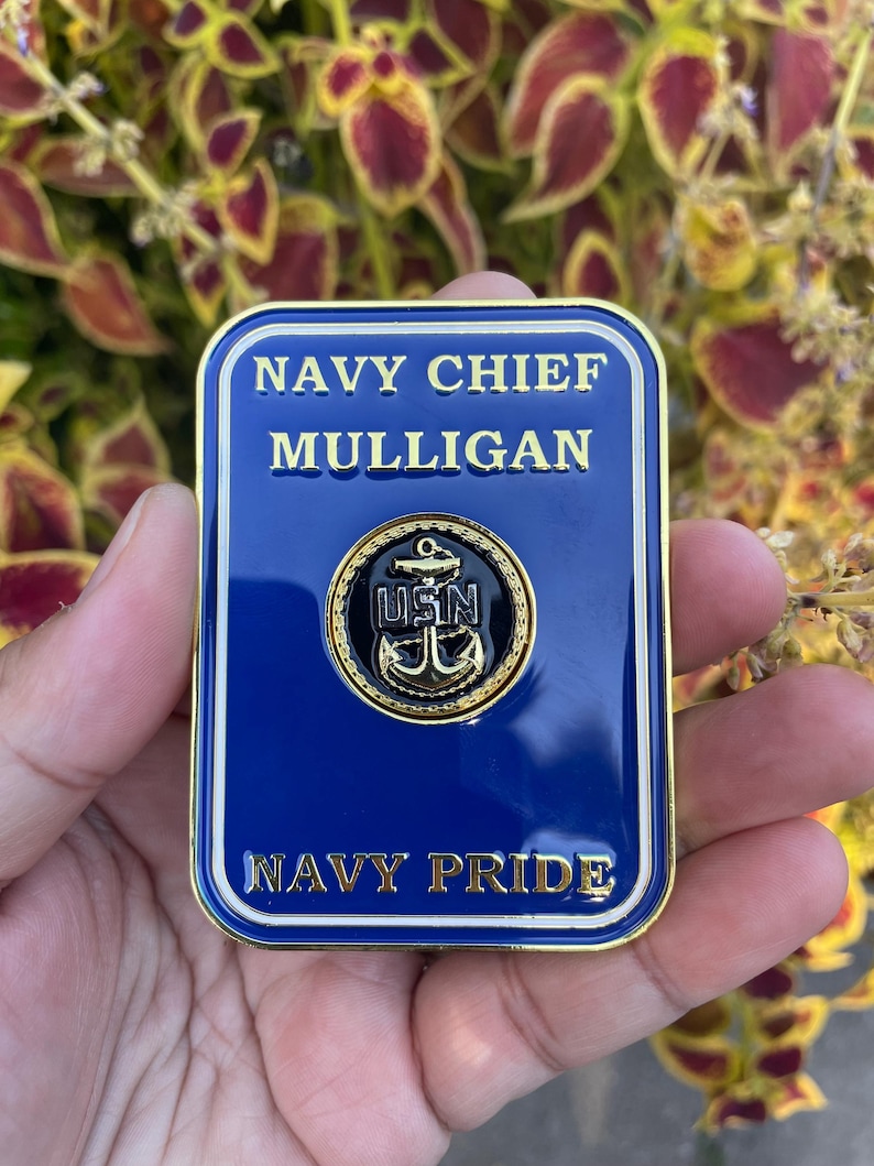 K&ouml;nnte beinhalten: Eine goldfarbene Metall-Challenge-M&uuml;nze mit blauem Hintergrund. Die M&uuml;nze zeigt den Text "NAVY CHIEF MULLIGAN" und "NAVY PRIDE" in goldenen Buchstaben. Ein goldfarbener Anker mit dem Text "USN" ist in der Mitte der M&uuml;nze platziert.
