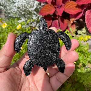 May include: A black turtle figurine with intricate details on its shell. The turtle is made of a smooth, polished material and has a realistic appearance.