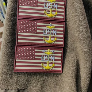 May include: Three red, white, and blue American flag patches with a gold anchor and the letters "USN" in white.