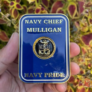 K&ouml;nnte beinhalten: Eine goldfarbene M&uuml;nze mit blauem Hintergrund. Die M&uuml;nze tr&auml;gt den Text "NAVY CHIEF MULLIGAN" und "NAVY PRIDE" in goldenen Buchstaben. In der Mitte der M&uuml;nze befindet sich ein goldener Anker mit einem blauen Kreis darum und dem Text "USN" in wei&szlig;en Buchstaben.