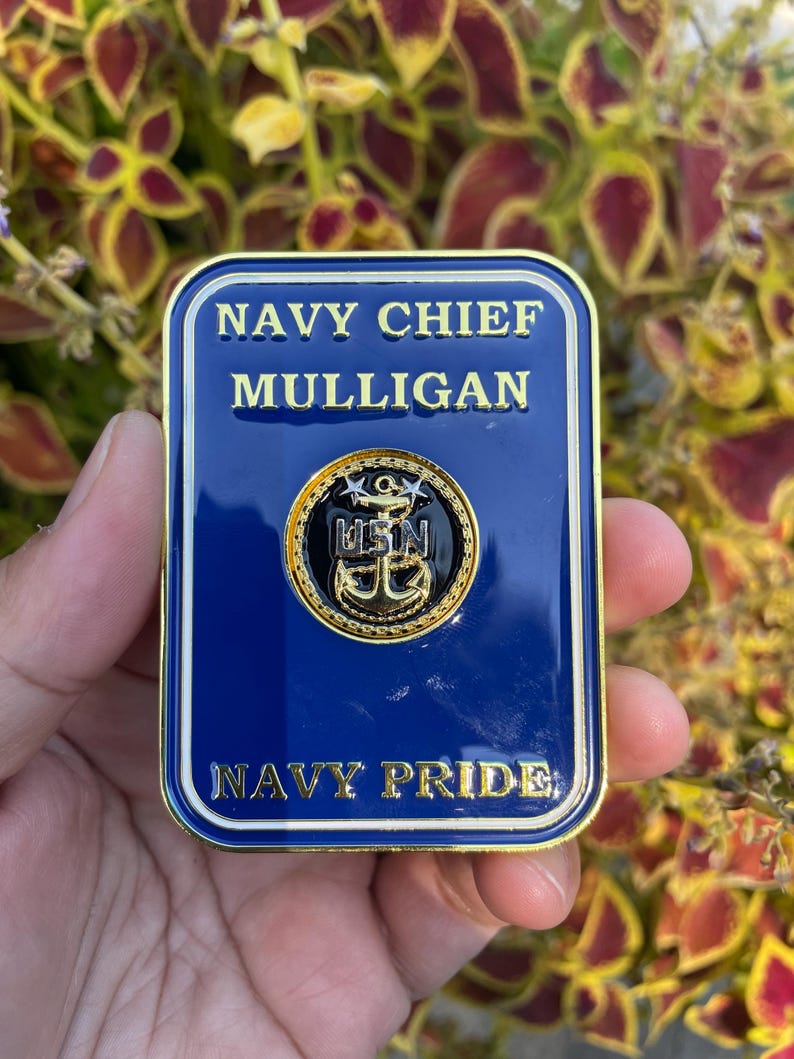 K&ouml;nnte beinhalten: Eine goldfarbene M&uuml;nze mit blauem Hintergrund. Die M&uuml;nze tr&auml;gt den Text "NAVY CHIEF MULLIGAN" und "NAVY PRIDE" in goldenen Buchstaben. In der Mitte der M&uuml;nze befindet sich ein goldener Anker mit einem blauen Kreis darum und dem Text "USN" in wei&szlig;en Buchstaben.