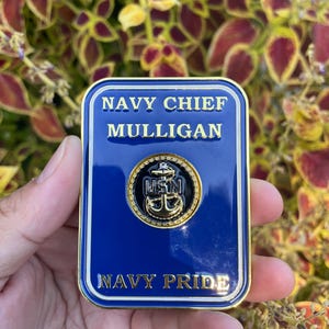 K&ouml;nnte beinhalten: Eine goldfarbene Challenge-M&uuml;nze mit blauem Hintergrund. Die M&uuml;nze zeigt den Text "NAVY CHIEF MULLIGAN" und "NAVY PRIDE" in wei&szlig;en Buchstaben. Ein goldfarbener Anker mit den Buchstaben "USN" befindet sich in der Mitte der M&uuml;nze.