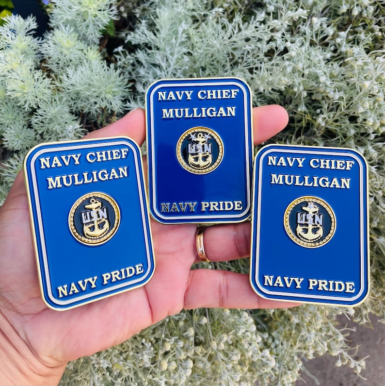 K&ouml;nnte beinhalten: Drei goldfarbene Pins mit blauem Hintergrund und wei&szlig;er Beschriftung. Die Pins zeigen "Navy Chief Mulligan" und "Navy Pride". Jeder Pin zeigt einen goldfarbenen Anker mit den Buchstaben "USN" darauf.