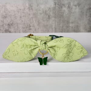 May include: A light green dog collar with a floral pattern and a green butterfly charm.