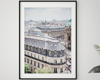May include: A black and white photograph of a Parisian cityscape, featuring a view of the rooftops of buildings and a church steeple in the distance.