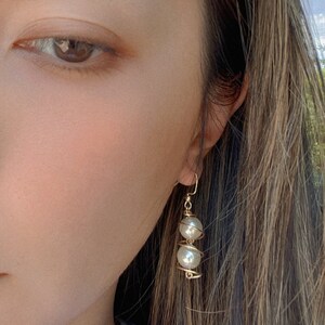 May include: Gold wire earrings with two white pearl beads.