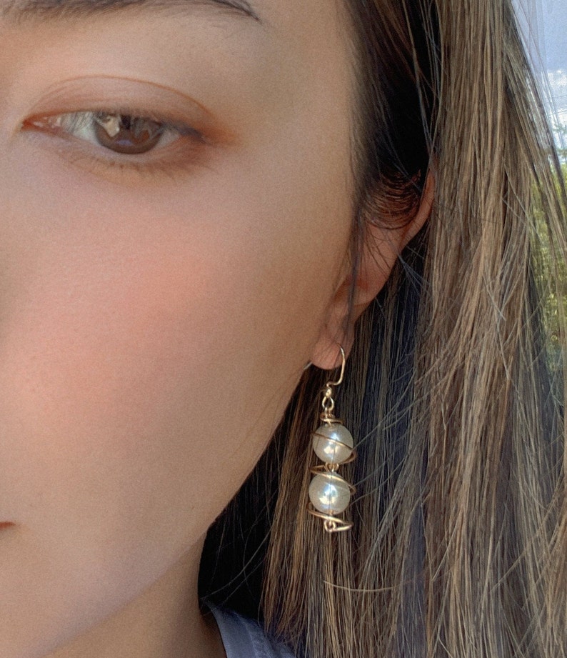 May include: Gold wire earrings with two white pearl beads.