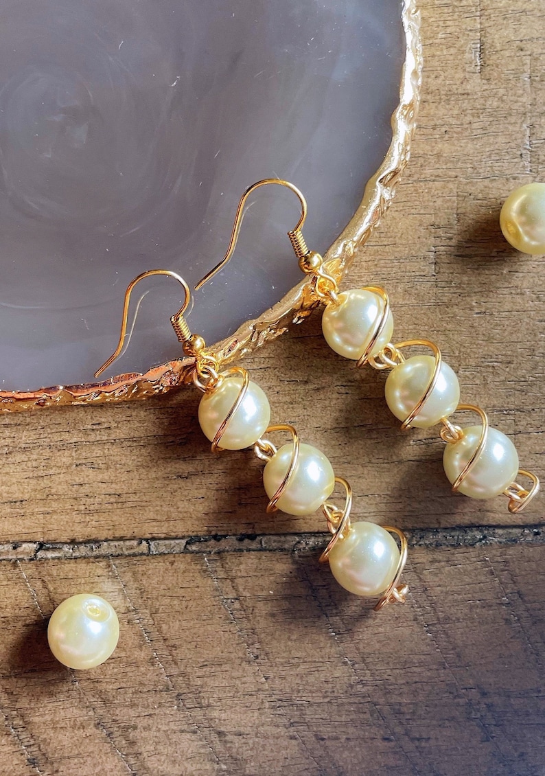 May include: A pair of gold earrings with a spiral design and white pearl beads.