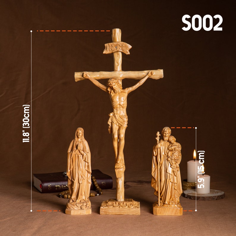 May include: A set of three wooden religious figurines, including a crucifix with the inscription "INRI", a statue of the Virgin Mary, and a statue of Saint Joseph with the baby Jesus. The figurines are all carved from wood and have a natural finish. The crucifix is 11.8 inches (30 cm) tall, and the other two figurines are 5.9 inches (15 cm) tall.