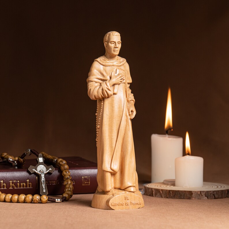May include: A wooden statue of Saint Martin de Porres, a Catholic saint, standing with his hands clasped in prayer. The statue is on a wooden base with the inscription "St. Martin de Porres".