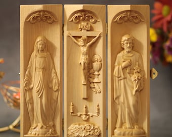 Könnte beinhalten: Ein dreiteiliges Holzrelief mit drei geschnitzten Tafeln, die die Jungfrau Maria, Jesus am Kreuz und den Heiligen Josef darstellen. Die Tafeln sind mit Scharnieren verbunden und können zusammengeklappt werden. Der Text "AVE MARIA" ist unter der Jungfrau Maria und "ST. JOSEPH" unter dem Heiligen Josef eingemeißelt.