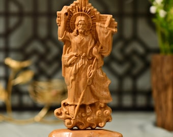 May include: A wooden sculpture of Jesus Christ carrying a cross. The sculpture is carved in a realistic style and depicts Jesus with a crown of thorns and a long robe. The sculpture is standing on a cloud and is surrounded by a halo.