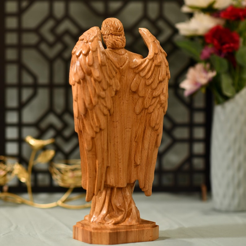 May include: A wooden angel figurine with outstretched wings. The angel is carved from a light brown wood and has a detailed design.