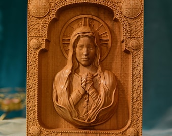 May include: A wooden carving of the Virgin Mary with a halo and rosary beads. The carving is framed in a detailed wooden frame.