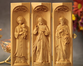 Könnte beinhalten: Ein dreiteiliges Holztriptychon mit drei geschnitzten Tafeln, die Unsere Liebe Frau von Lavang, Jesus und den Heiligen Josef darstellen. Die Tafeln sind mit Scharnieren versehen und können zusammengeklappt werden. Der Text "Unsere Liebe Frau von Lavang", "Jesus, ich vertraue auf dich" und "Heiliger Josef" ist auf der Unterseite jeder Tafel aufgedruckt.