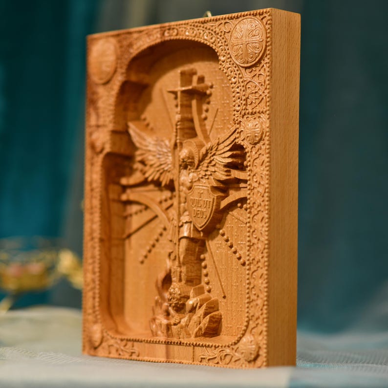May include: A wooden carving of an angel with wings spread wide, holding a cross and a shield with the text "VIGILAT DEUS" on it. The carving is surrounded by intricate details and a decorative frame.