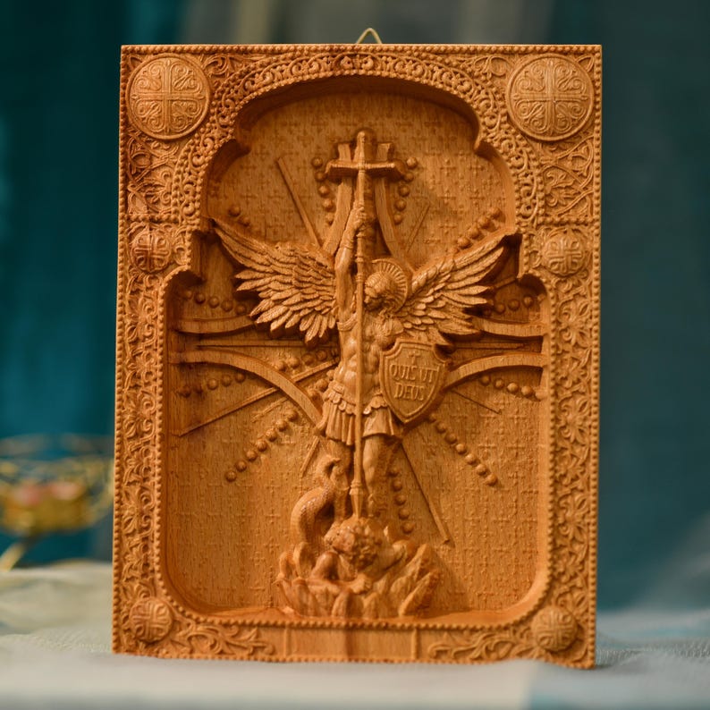 May include: A wooden carving of the Archangel Michael, a Christian angel, standing on a dragon. The angel is holding a sword and a shield with the inscription "QUI UT DEUS" on it. The carving is surrounded by a decorative frame.