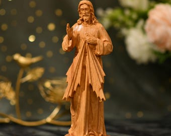 May include: A wooden statue of Jesus Christ with his heart exposed and a crown of thorns. He is wearing a robe and has a sorrowful expression on his face.