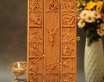 Könnte beinhalten: Ein dreiteiliges Holzrelief mit 14 geschnitzten Szenen, die die Kreuzwegstationen darstellen. Jede Szene ist mit römischen Ziffern nummeriert. Das Triptychon ist geschlossen und zeigt die zentrale Szene von Jesus am Kreuz.