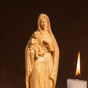May include: A wooden statue of the Virgin Mary holding a baby Jesus. The statue is carved with intricate details and has a warm, natural wood finish.