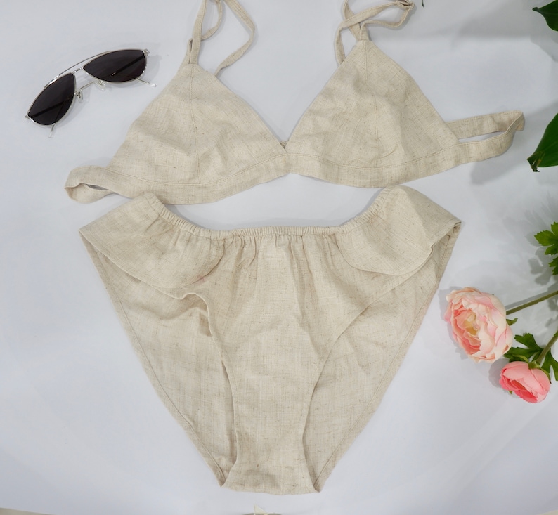 May include: A beige linen lingerie set with a triangle bra and ruffled panty.