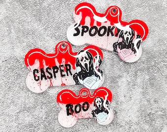 May include: Three white bone-shaped dog tags with red paint splatter and a ghost face graphic. The tags are labeled "Spooky", "Casper", and "Roo".