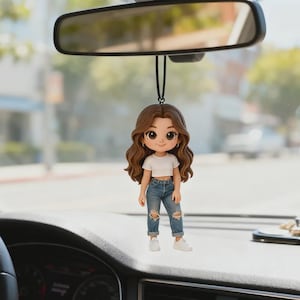 Peut inclure: Un porte-bonheur de voiture représentant une figurine de dessin animé d'une personne aux cheveux bruns, vêtue d'un crop top blanc, d'un jean bleu déchiré et de baskets blanches. Le charme est suspendu à un fil noir, accroché au rétroviseur d'une voiture.