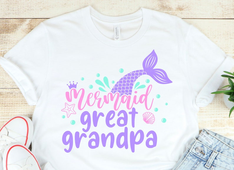 May include: White t-shirt with a purple mermaid tail, pink crown, and the text "Mermaid Great Grandpa" in purple and pink.