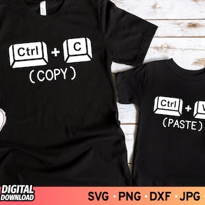 May include: Two black t-shirts with white text. The larger shirt says "Ctrl + C (COPY)". The smaller shirt says "Ctrl + V (PASTE)".