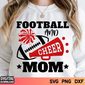 May include: White sweatshirt with a black and red graphic. The graphic includes a football, a red megaphone with the word "CHEER", and the words "FOOTBALL AND MOM". A red and white pom-pom is also included.