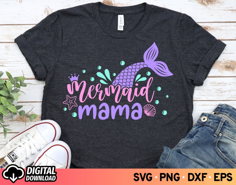 May include: A dark gray t-shirt with a purple mermaid tail and the text "mermaid mama" in pink and purple lettering. The design also includes a crown, starfish, seashells, and bubbles.